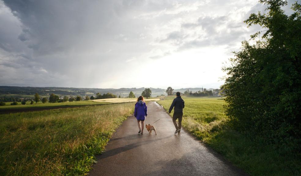 Man and Woman Walking Dog on Tarmacked Road Man and Woman Walking Dog on Tarmacked Road